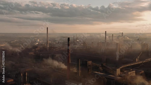 Drone shot of industrial zone with thick smog and burning fossil fuels. Factory zone pan shot from left to right, air pollution and soot in many factory chimneys in city area