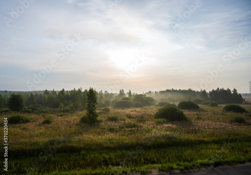 sunrise in the morning in a haze of fog over buildings, trees and fields © константин константи