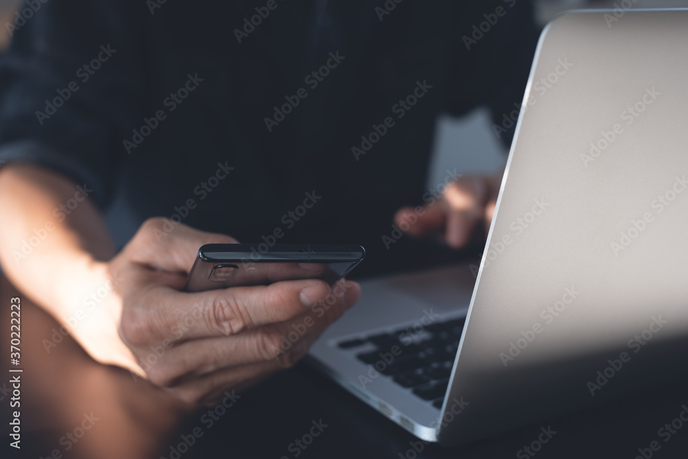 Man using mobile phone and online working on laptop computer for telework concept Man using mobile phone and online working on laptop computer for telework concept