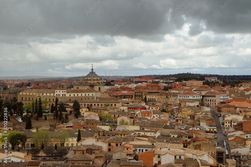 Urban texture. Cityscape. View of the ancient buildings and houses in the city of Toledo, Spain, under a cloudy sky. The Primate Cathedral of Saint Mary dome in the background.