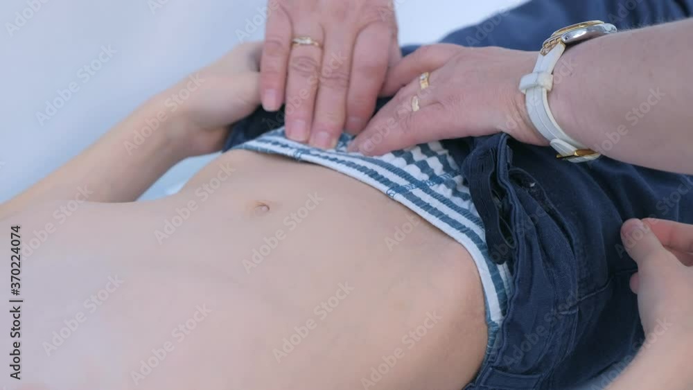 Doctor pediatrician woman examining child boy abdomen tummy in hospital, hands closeup. Checkup stomach and belly on pediatric checkup appointment. Children medical healthcare concept. Doctor pediatrician woman examining child boy abdomen tummy in hospital, hands closeup. Checkup stomach and belly on pediatric checkup appointment. Children medical healthcare concept.