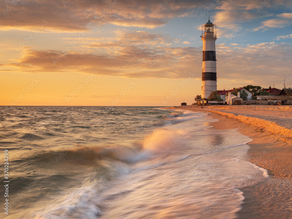 long exposure of sea water in view to  lighthouse in golden hour at sunset