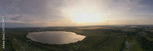 panoramic landscape of lake and forest around in summer at dawn filmed from a drone