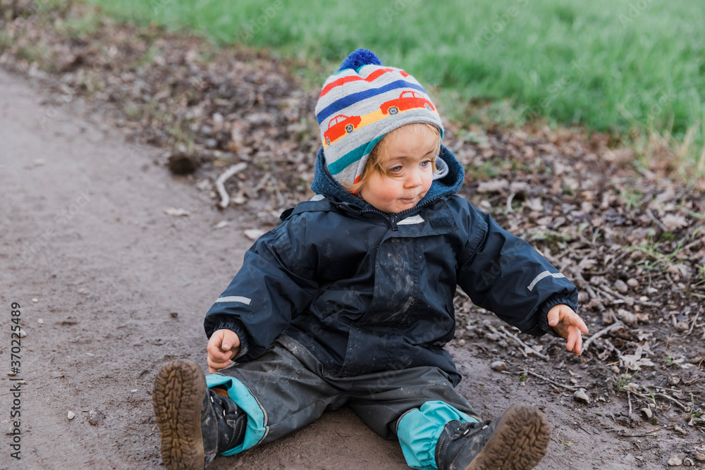Toddler girl sitting with muddy pants on dirt road Toddler girl sitting with muddy pants on dirt road
