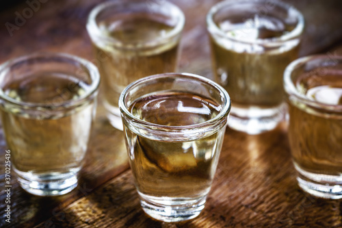 Glasses of Brazilian gold cachaça, distilled drink, on rustic wooden background.