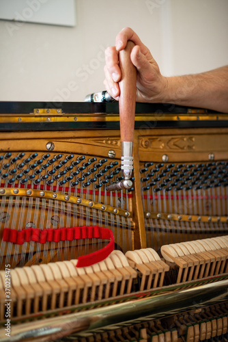 Technician, tuning a piano. Piano tuning is the act of adjusting the tension of the strings of an acoustic piano so that the musical intervals between strings are in tune.