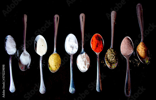spoons with spices on a black background