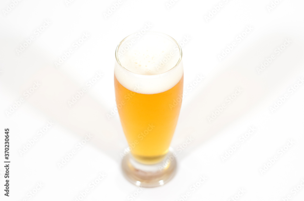 A glass of beer filled with foam centered in the image with a white background. A glass of beer filled with foam centered in the image with a white background.