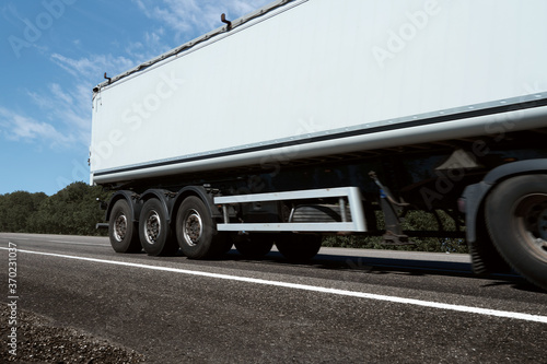 truck on the road, side view, empty space on a white container - concept of cargo transportation, trucking industry