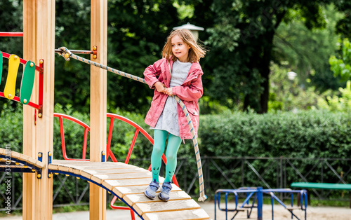 Fototapeta Naklejka Na Ścianę i Meble -  Little girl climbing rope on playground