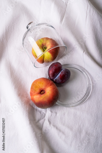 seasonal peaches and plums on white cloth