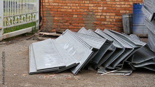 Perforated metal sheets lie on the street on the asphalt. Metal dump.