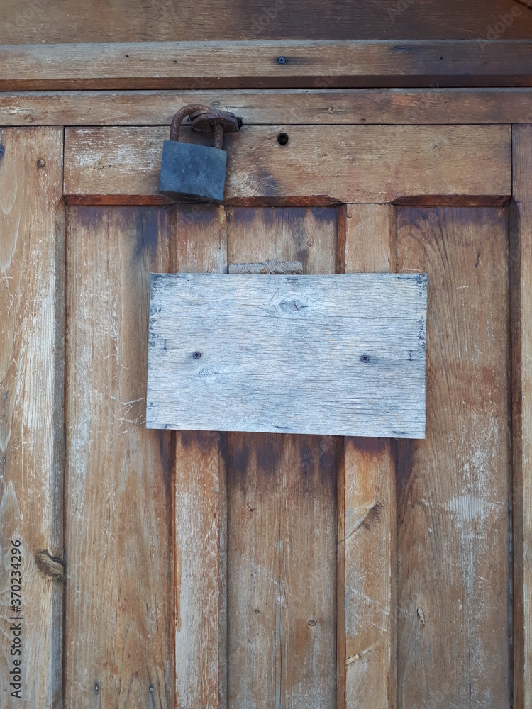 The sign on the old wooden door is not painted.