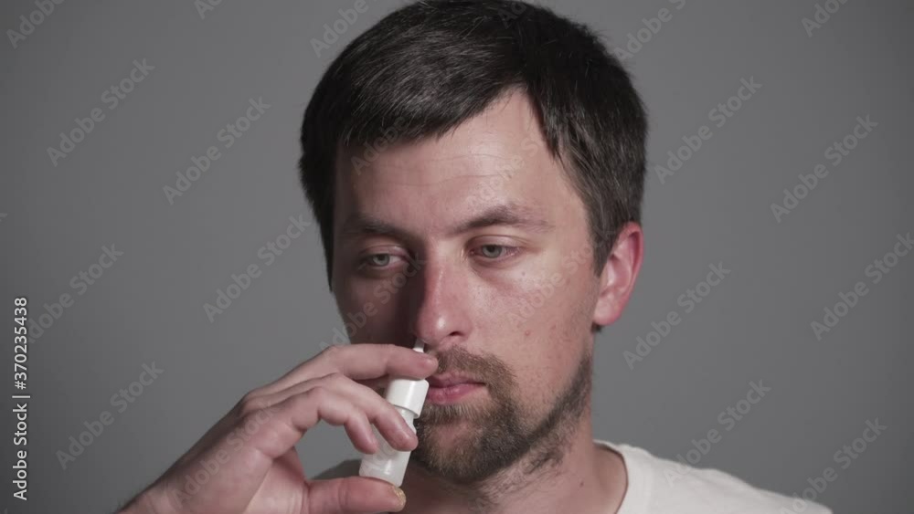 Young Caucasian man holds nasal spray for rhinitis and allergies in his