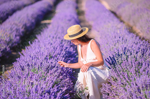 Woman in lavender flowers field in white dress and hat