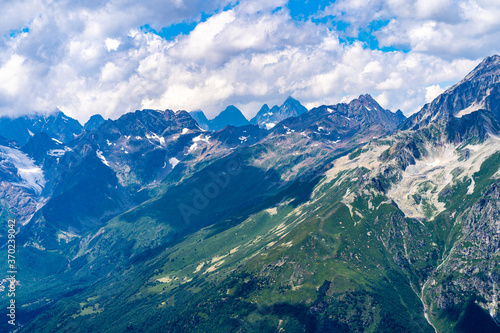 Peaks of magnificent rocks located against bright cloudy sky on sunny day in nature