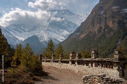 Ancient Mani wall against the backdrop of mighty Annapurna II peak. Annapurna Circuit, Greater Himalayas, Nepal photo