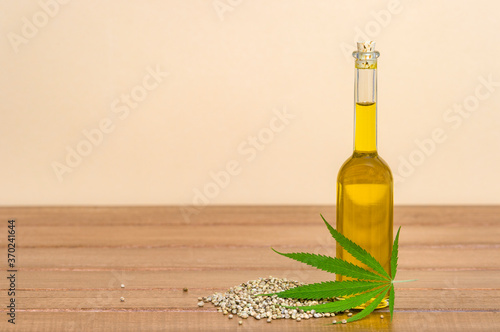 Green marijuana leaf, hemp seeds and cannabis oil on wooden background. Alternative medicine. Vegetarian food concept