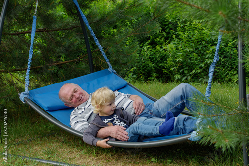 grandfather and grandson relax on a garden swing