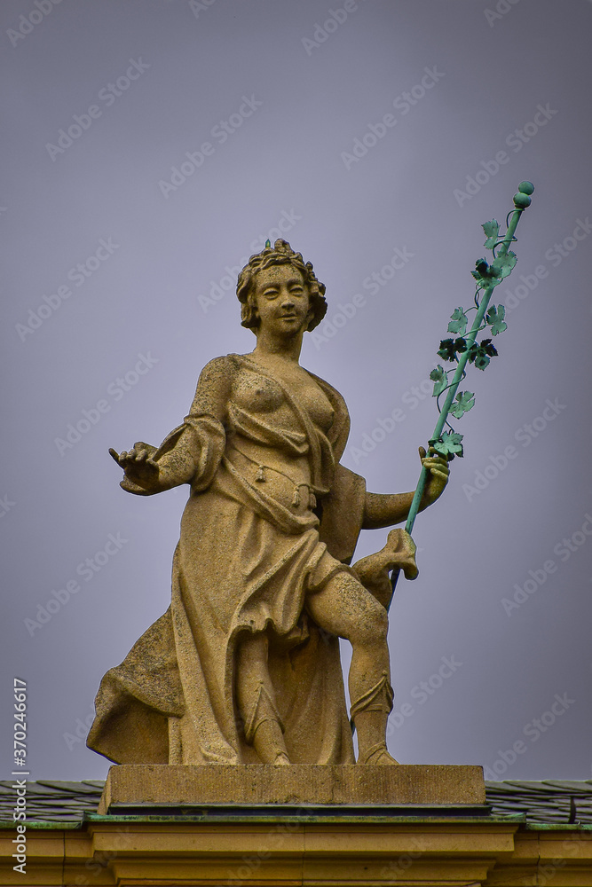 Fototapeta premium A fragment of the roof of a building with a sculpture of a woman holding a vine