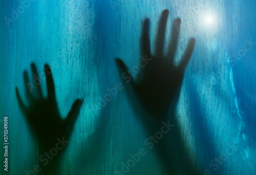 Closeup of scary silhouette of female hands through fabric at night.