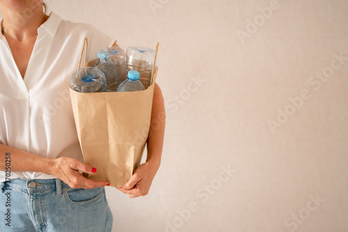 unrecognizable woman holding a paper bag with plastic bottles in her hands. rubbish reuse, environmental pollution. pure planet. recycling concept.  plastic problem