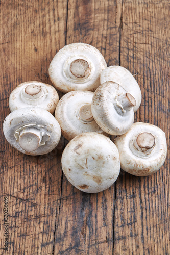 stack of raw fresh champignon mushrooms close up on a wooden rustic background