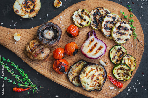 Grilled vegetables on cutting board on black slate stone background. View from above.