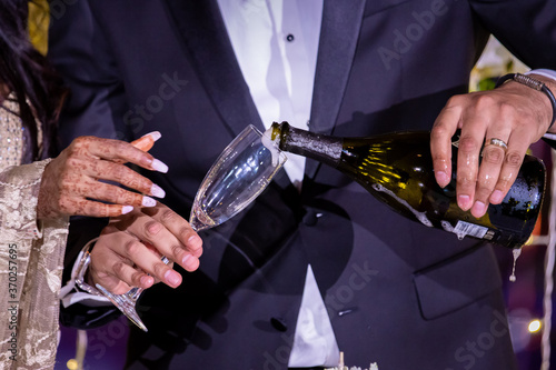 Indian married couple's hands holding champagne glasses