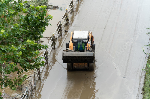 Due to the flood, mud piled up on the riverside bike paths is being cleaned up with skid loader © ToriNim