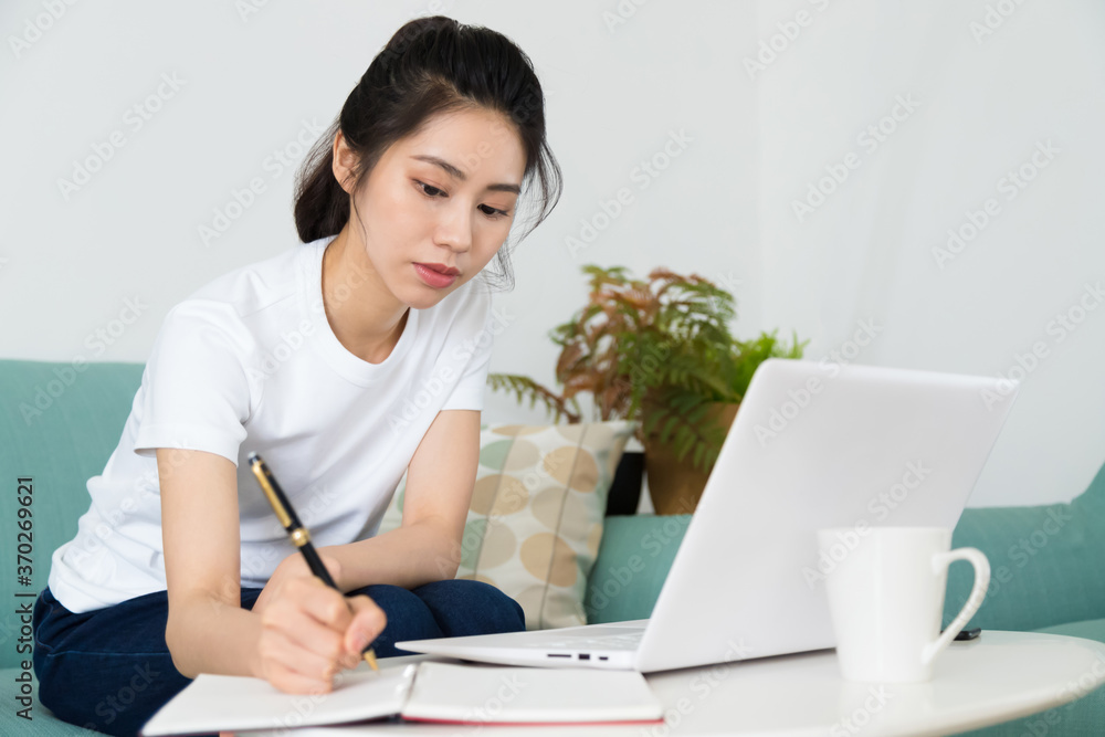 Portrait of a pretty young woman studying while sitting at the table with laptop at home. Portrait of a pretty young woman studying while sitting at the table with laptop at home.