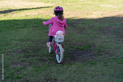 Fototapeta Naklejka Na Ścianę i Meble -  Young child girl learning to ride a bike at the local park