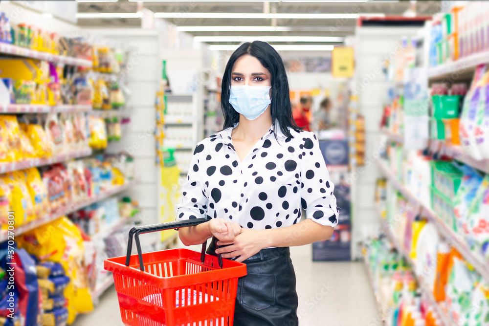 girl in a protective mask makes purchases in the supermarket. Girl holding a basket for groceries and purchases