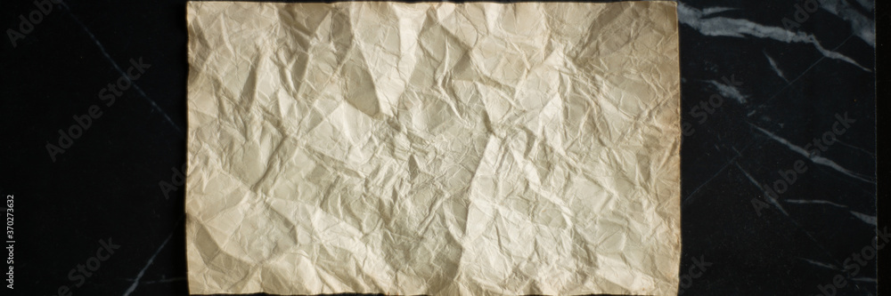 rumpled sheet of old paper on a black background rumpled sheet of old paper on a black background