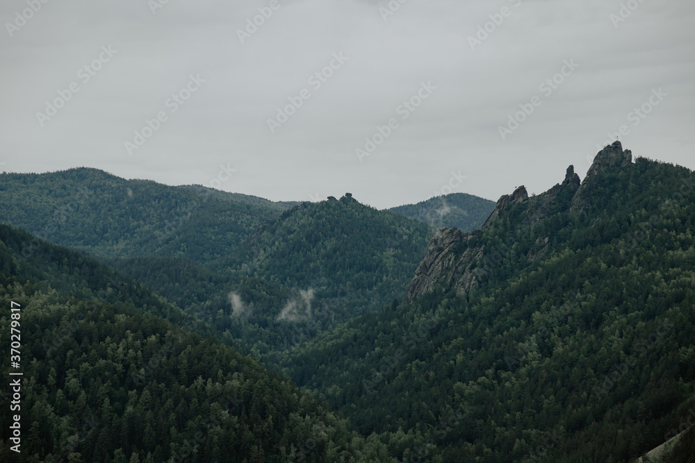 Gloomy view to great mountains under dark gray cloudy sky. Dramatic  landscape with  mountains in rainy weather. Atmospheric scenery with giant mountain ridge in overcast darkness.