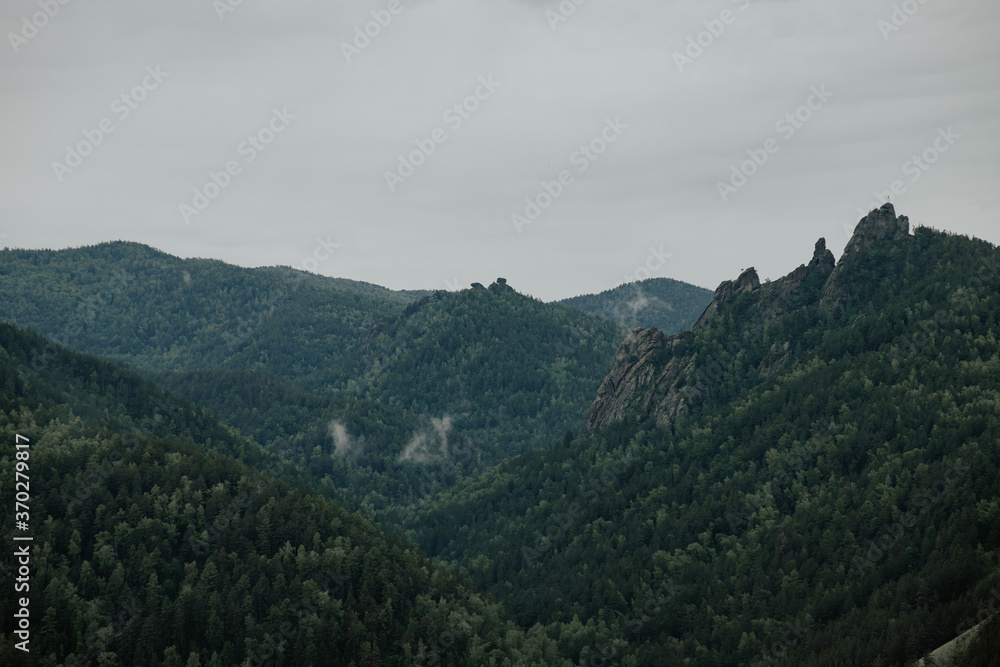 Gloomy view to great mountains under dark gray cloudy sky. Dramatic landscape with mountains in rainy weather. Atmospheric scenery with giant mountain ridge in overcast darkness. Gloomy view to great mountains under dark gray cloudy sky. Dramatic landscape with mountains in rainy weather. Atmospheric scenery with giant mountain ridge in overcast darkness.