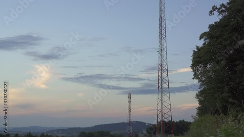 Telecommunication tower 5G with radio antennas in a green environment against sunset sky. Electromagnetic and microwaves background / pollution. photo