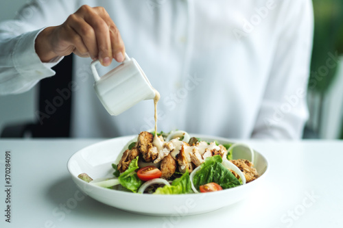 Foto Closeup image of a woman pouring dressing into a chicken salad