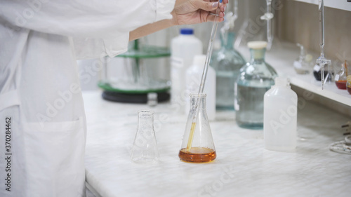 Female scientist with pipette analyzes liquid in distillery laboratory researcher. Analysis of whiskey sample on laboratory equipment.