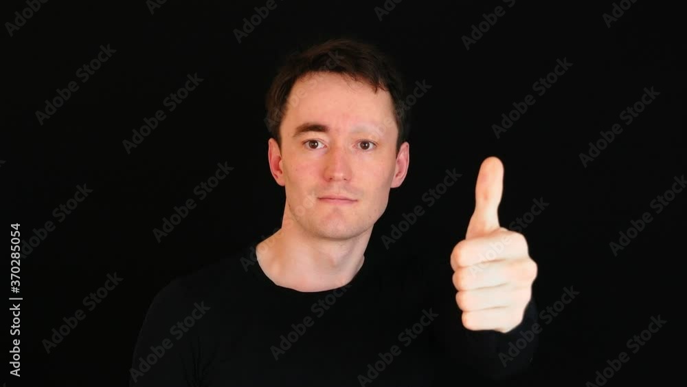 Man in Black on Black background shows thumbs up. A man without an eyebrow. Modern society concept Man in Black on Black background shows thumbs up. A man without an eyebrow. Modern society concept