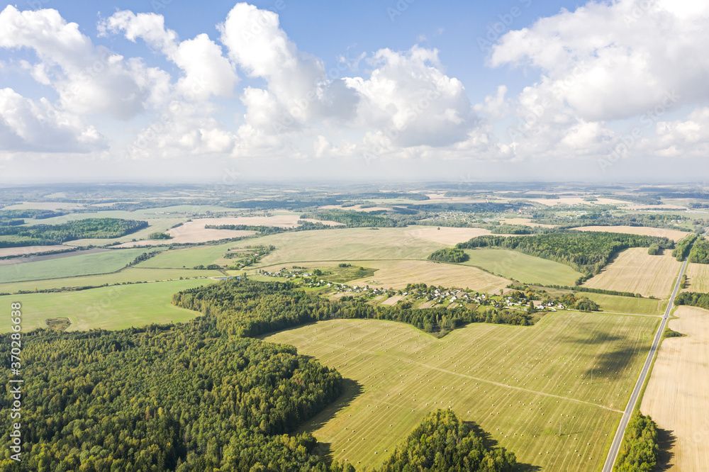 countryside landscape with agricultural fields and blue sky with fluffy white clouds. rural nature in the farm land. aerial view