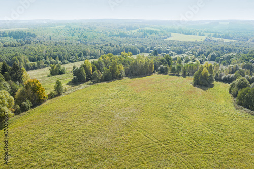 Fototapeta Naklejka Na Ścianę i Meble -  rural summer landscape with green meadow and forest on horizon. captured from above with a drone