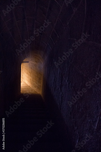 Mystery. View of a dark stone underground tunnel leading to the light at the end of the corridor.  