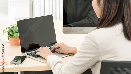 Asian business woman working at her office via laptop. Rear side of young female manager using computer at workplace