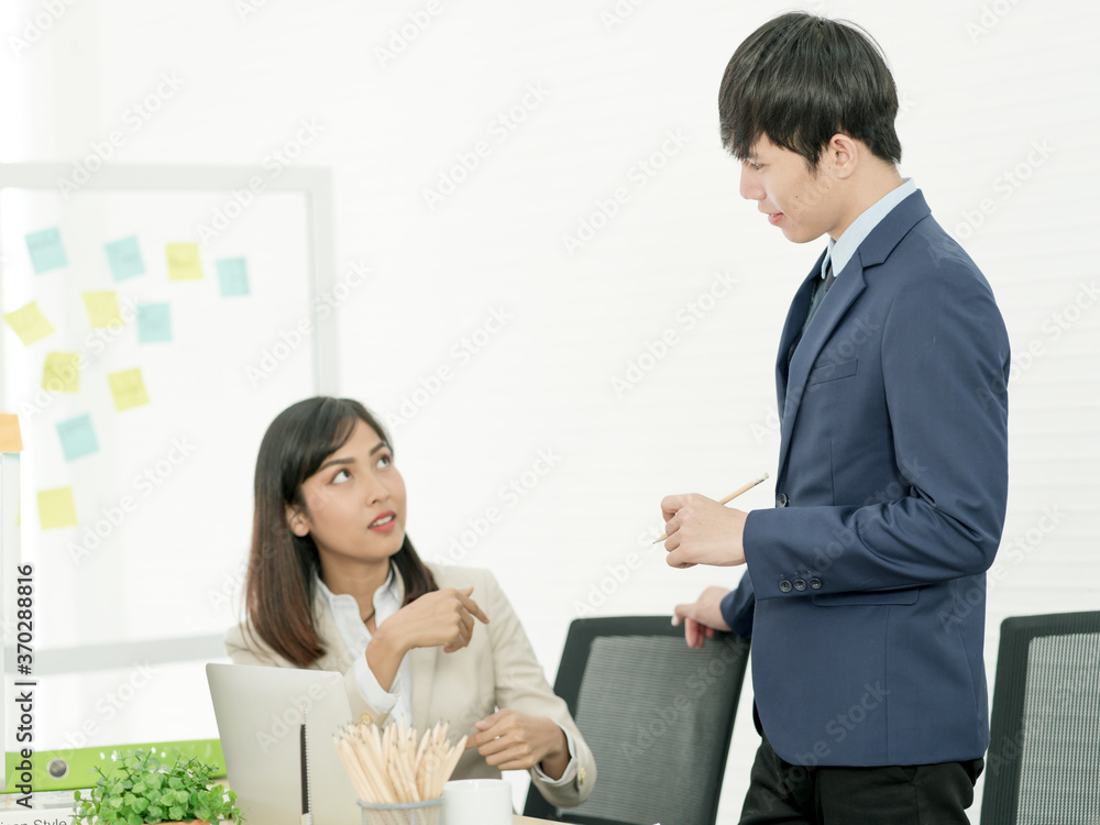 Asian business people having a casual discussion. Staff standing and discussing work in office. Asian business people having a casual discussion. Staff standing and discussing work in office.