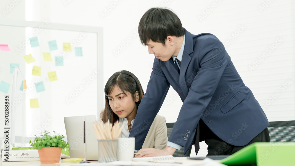 Asian business people having a casual discussion. Staff standing and discussing work in office. Asian business people having a casual discussion. Staff standing and discussing work in office.