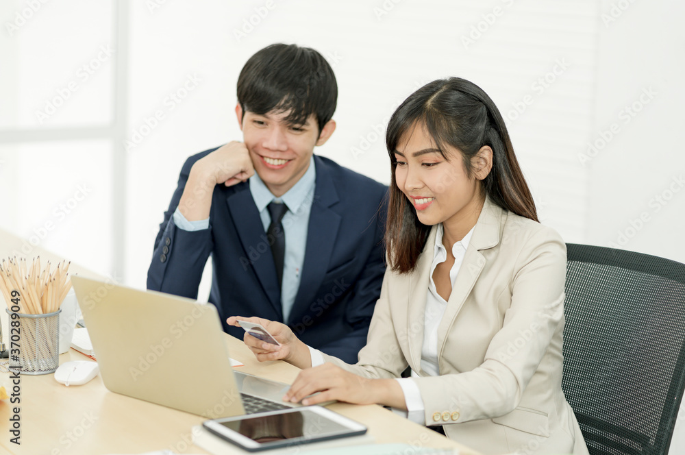 Asian staff holding credit card and using laptop computer in office. Online Shopping, internet banking, spending money Asian staff holding credit card and using laptop computer in office. Online Shopping, internet banking, spending money
