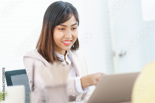 Asian business woman working at her office via laptop. Young female manager using computer at workplace