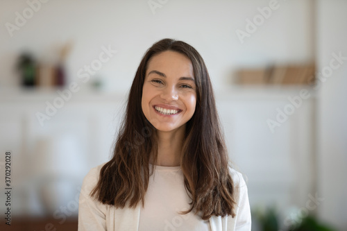 Fototapeta Naklejka Na Ścianę i Meble -  Head shot profile picture of smiling attractive mixed race woman. Happy caucasian girl looking at camera, enjoying communicating with friends via video call, female client satisfied with service.