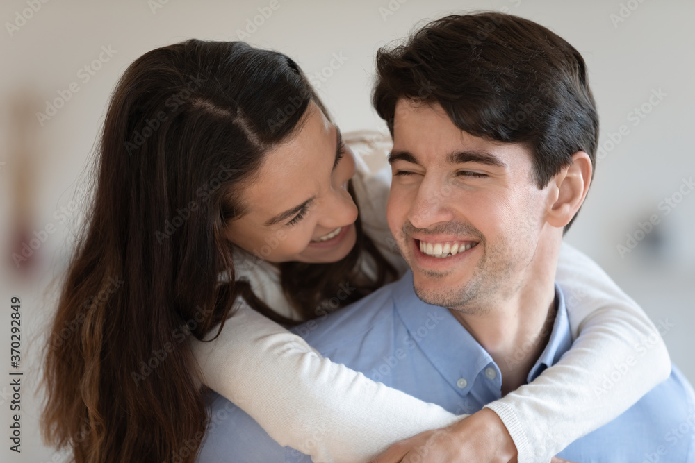 Pretty mixed race woman cuddling happy handsome husband, enjoying tender sweet moment at home, close up. Smiling sincere married young family couple reconciling after quarrel, good relations concept. Pretty mixed race woman cuddling happy handsome husband, enjoying tender sweet moment at home, close up. Smiling sincere married young family couple reconciling after quarrel, good relations concept.